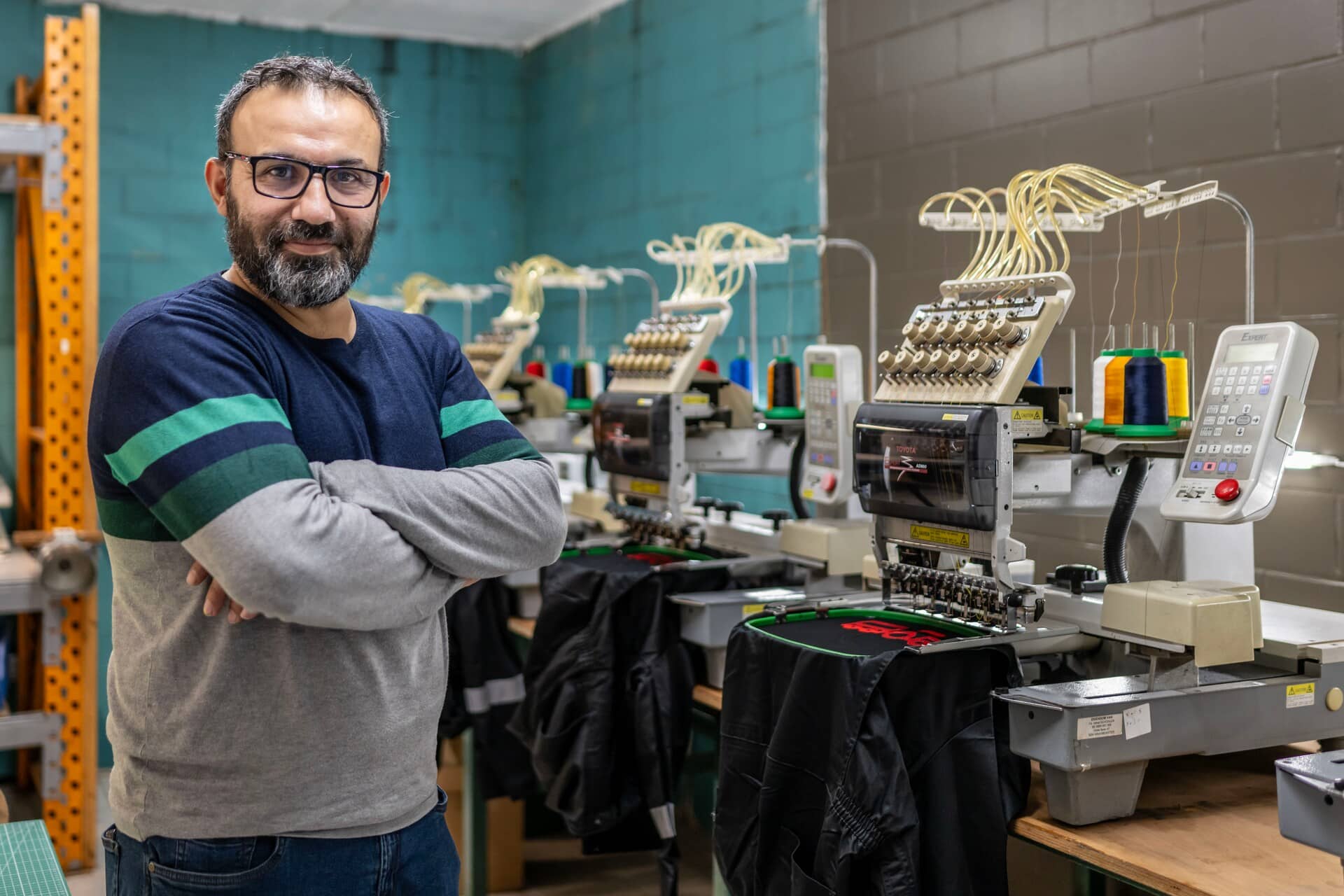 Tailors work on vintage sewing machines in a busy workshop.